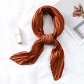 Detailed view of caramel pleated satin silk scarf with elegant fold textures on white surface - Caramel
