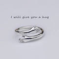 Macro detail of silver hugging hands ring featuring an adjustable open band design - Adjustable / Silver