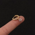 Makroaufnahme goldener Blumen-Ohrringe mit glitzernder Zirkon-Einlage auf schwarzem Grund - Silber / Blume