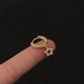 Nahaufnahme eines goldenen Sternohrrings mit Zirkonia-Kristallen, an einem Finger präsentiert - Silber / Pentagramm