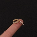 Nahaufnahme vergoldeter Blumen-Ohrring mit Zirkonia-Besatz auf dem Finger präsentiert - Silber / Kreuz