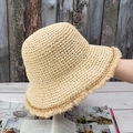 Detailed close-up of beige crochet straw bucket hat with vintage frayed brim details - Adjustable / Beige