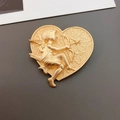 Vintage Brosche in Herzform aus mattem Gold mit barockem Amor-Relief auf grauem Grund - Amor Brosche