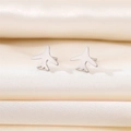 Polished stainless steel airplane stud earrings displayed on elegant beige silk fabric - Silver