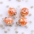 Macro detail of four orange star sequin glass globe charms with golden metal loops - Orange