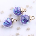 Detalle de esferas de cristal transparente con lentejuelas de estrellas para hacer joyas - Morado