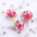 Close-up of glass orb charms filled with pink star sequins and golden metal loops - Red