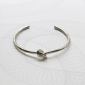 Dettaglio ravvicinato di un bracciale a fascia con nodo in metallo lucido color argento - Argento