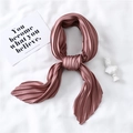 Detail of pleated silk-like scarf in rose pink laid on white fabric with artistic decor - Dusty Pink
