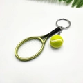 Dettaglio di un portachiavi con mini racchetta da tennis e pallina gialla sportiva - Verde