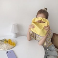 Minimalist yellow baguette bag with ruched handle held by a model in casual wear - Lemon Yellow
