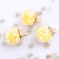 Close-up of clear crystal glass ball pendants with yellow star sequins and gold metal rings - Yellow