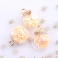 Macro shot of glass ball pendants with star sequins and gold hooks for DIY jewelry - Apricot