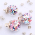 Detail of transparent glass globe pendants with colorful star sequins and gold hooks - Clear