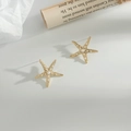 Pendientes de estrella de mar dorada con perlas blancas sobre fondo minimalista gris claro - Botones de Perla de Estrella de Mar / Dorado