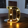 Golden LED letter D light with warm bulbs on wood desk for romantic decor - Letter D