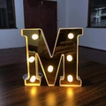 Golden 16cm LED letter M lamp with warm lights and reflective finish on wood - Letter M