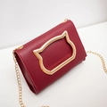 Fashionable burgundy crossbody bag with distinctive gold cat head buckle and chain strap - Red
