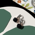 Dettaglio di orecchini con pietra nera quadrata e montatura in argento micro-pavé su sfondo - Nero