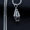Macro shot of silver stainless steel praying hands pendant on a dark textured surface - Praying Hands + Steel Chain
