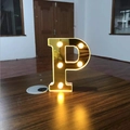 Golden mirror finish letter P LED light with warm white glow on a wooden surface - Letter P
