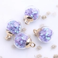 Detalle de bolas de cristal con lentejuelas de estrellas púrpuras y azules y aros de oro - Violeta Claro