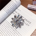 Makroaufnahme der glitzernden Blumen-Handyhalterung aus Kristall auf einem Buch - Edelstein Halter-Nr.5 Satellit Langer Diamant-Silberne Basis