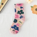 Rosa Baumwollsocken mit bunten Blumenmustern auf weißem Stoffhintergrund - Rosa