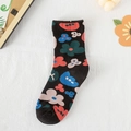 Schwarze Baumwollsocken mit lebendigen bunten Blumenmustern auf weißem Stoffhintergrund - Schwarz