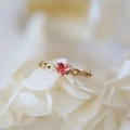 Elegant gold heart ring with pink gemstone and zircon on white petals background - Gold Red Zirconia