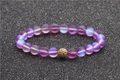 Détail de perles de pierre de lune givrées avec boule de cristal dorée sur fond noir - Violet