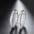 Macro detail of silver hoop earrings with square-cut cubic zirconia in prong setting - White Gold