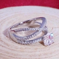 Intertwined silver ring with a brilliant round zircon on a natural wood surface - US 6 / Silver