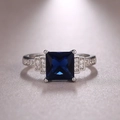 Macro d'une bague en zircon bleu carré avec pierres latérales sur monture en or blanc - US 6 / Bleu foncé