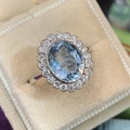 Detailed close-up of a floral halo copper ring with oval blue zircon on beige velvet - US 9 / Aqua