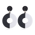 Dettaglio macro di orecchini pendenti geometrici in acrilico bianco e nero e oro metallo - Rotondo