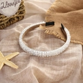 Close-up of handmade crystal beaded headband with intricate woven details on soft fabric - White