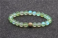 Bracelet en perles de pierre de lune avec boule de zircon doré sur fond noir scintillant - Vert clair