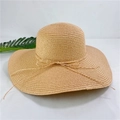 Detail shot of a natural straw sun hat with a wide brim and a delicate bow tie decoration - M (56-58cm) / Light Coffee