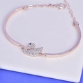 Detail of rose gold swan bangle with sparkling rhinestones on a white cushion - Swan Bracelet