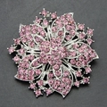 Pink rhinestone flower brooch with silver metal floral layers on a dark grey background - Pink