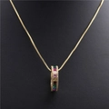 Vue macro d'un collier doré avec pendentif circulaire serti de zircons aux couleurs de l'arc-en-ciel - Doré