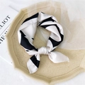 Elegant black and white patterned silk square scarf tied in a knot on a beige tray - Black and White Block