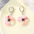 Dettaglio di un orecchino floreale con petali sfumati rosa su un vassoio beige - Fiore Rosa