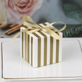 Square gold striped candy box with a satin bow on a decorative white ceramic plate - Gold and White Stripes + Gold Ribbon