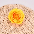 Artificial bright yellow rose flower head in full bloom on a rustic woven mat base - Yellow