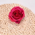 Artificial rose flower head in vibrant magenta silk on a woven straw mat - Rose Red