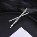 Barrette croisée argentée élégante ornée de strass brillants sur un fond noir texturé - Argenté