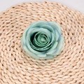 Artificial rose flower head in dusty blue color on a rustic woven mat surface - Green