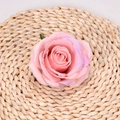 Artificial light pink rose flower head with green leaves on a woven straw mat - Orange Pink